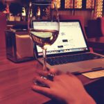 dame werkt op laptop met glas wijn erbij