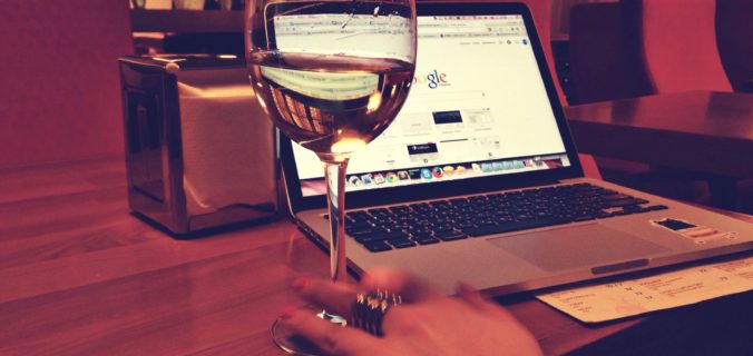 dame werkt op laptop met glas wijn erbij